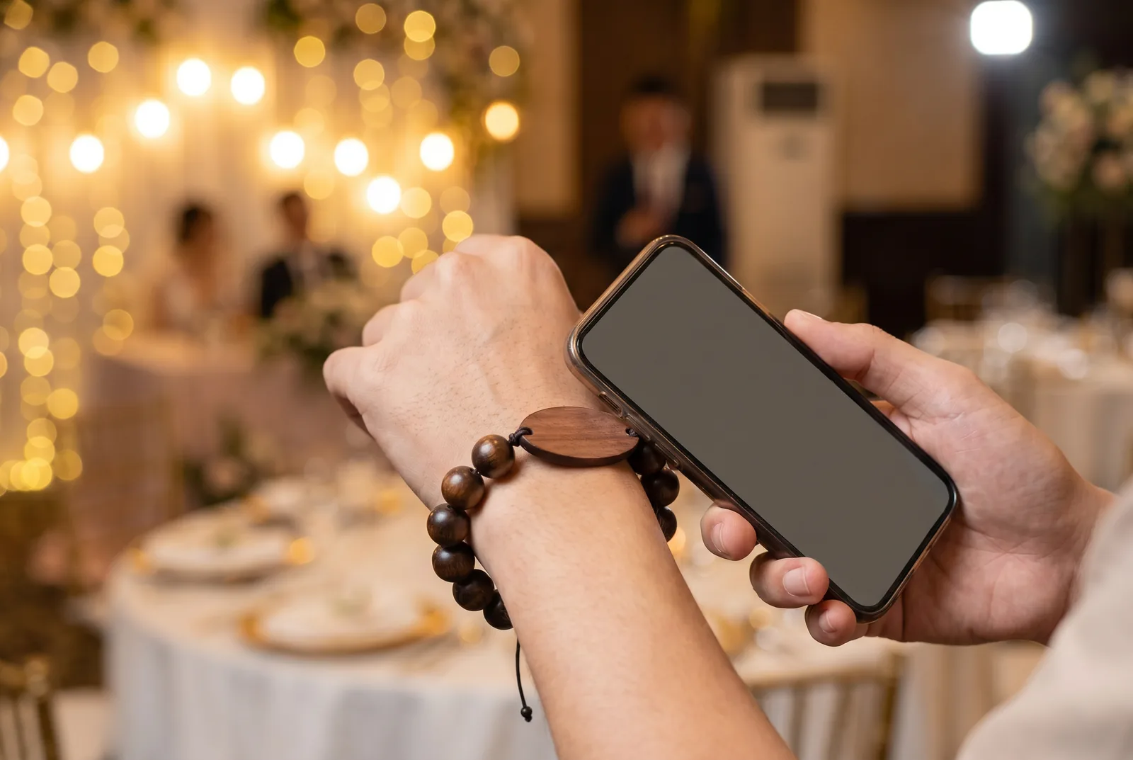 Wedding guest tapping a smartphone to the wooden bead NFC wristband to share photos at the reception