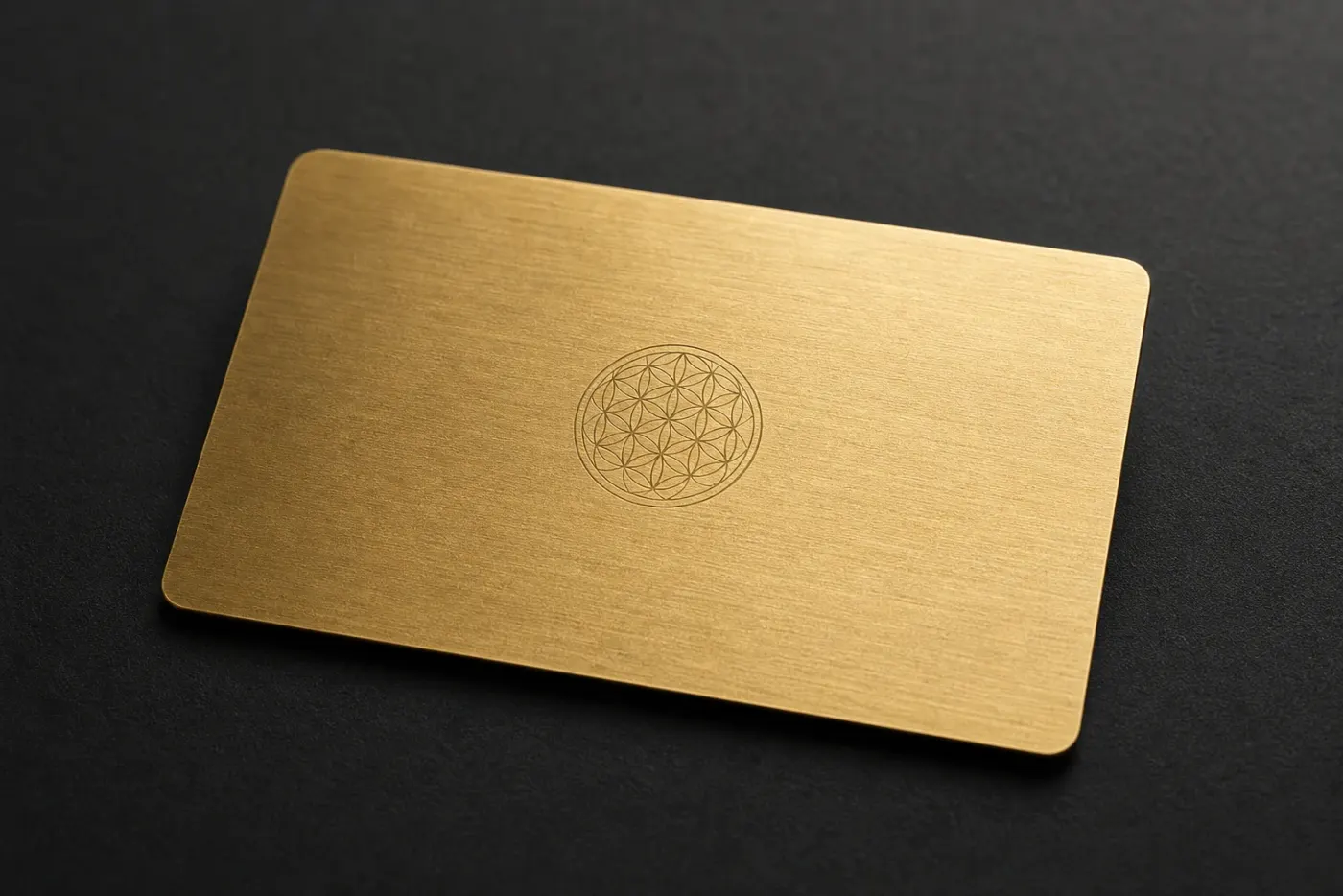 Brushed brass RFID card with a fine laser-engraved geometric medallion on a dark surface
