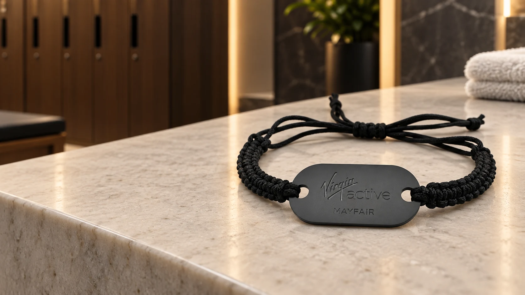 Custom Virgin Active Mayfair wristband fully visible on a stone counter in an illustrative club locker-room setting